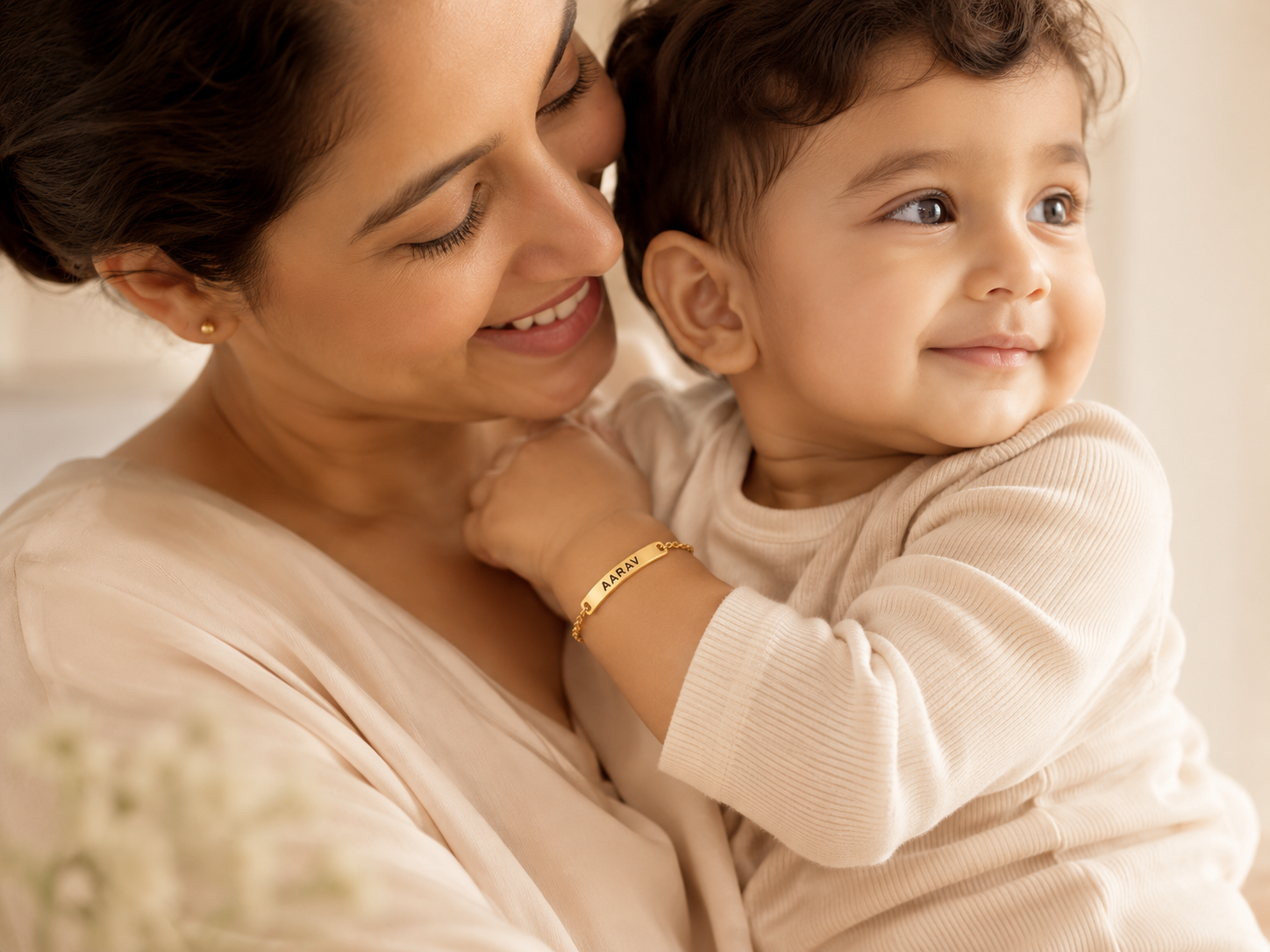 Mother holding her smiling baby, child wearing a personalized name bracelet